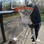 リングのフックにネットを丁寧に引っ掛ける交換作業の様子