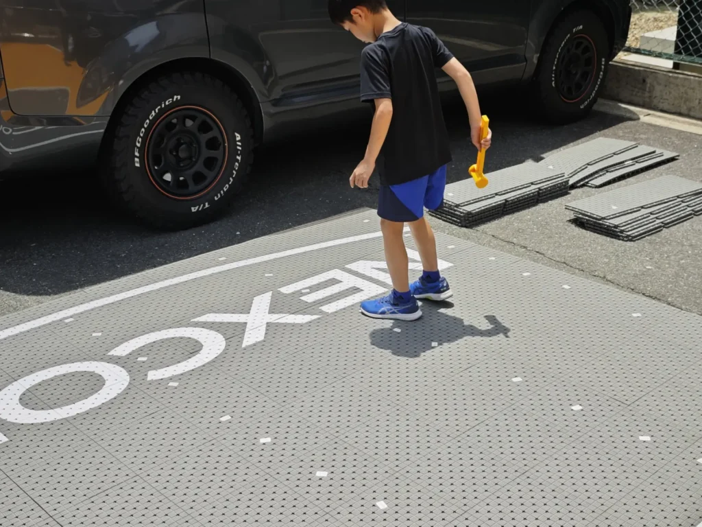 番号シール付きパネルを駐車場のコンクリートに並べて連結するDIY設置の様子